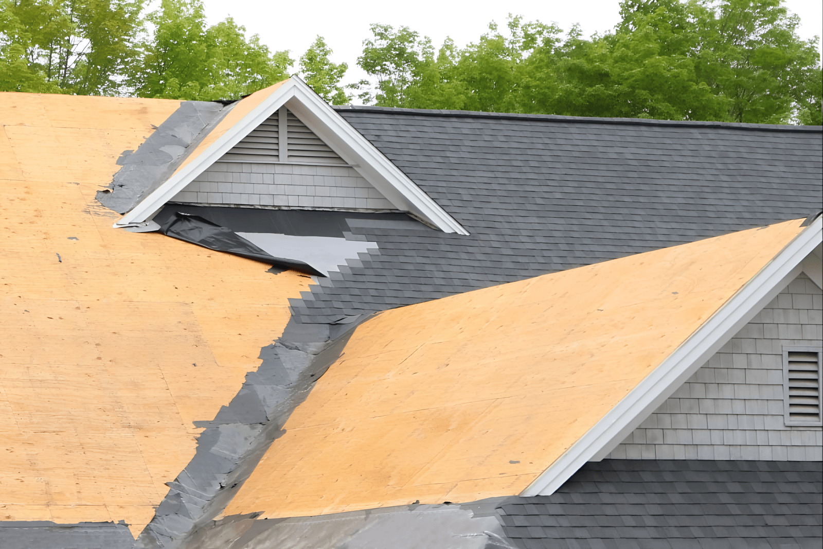 Storm-damaged roof mid tear-off showing exposed decking